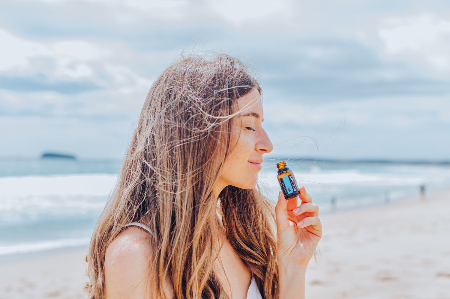 Woman holding a bottle of sunscreen on a beach
