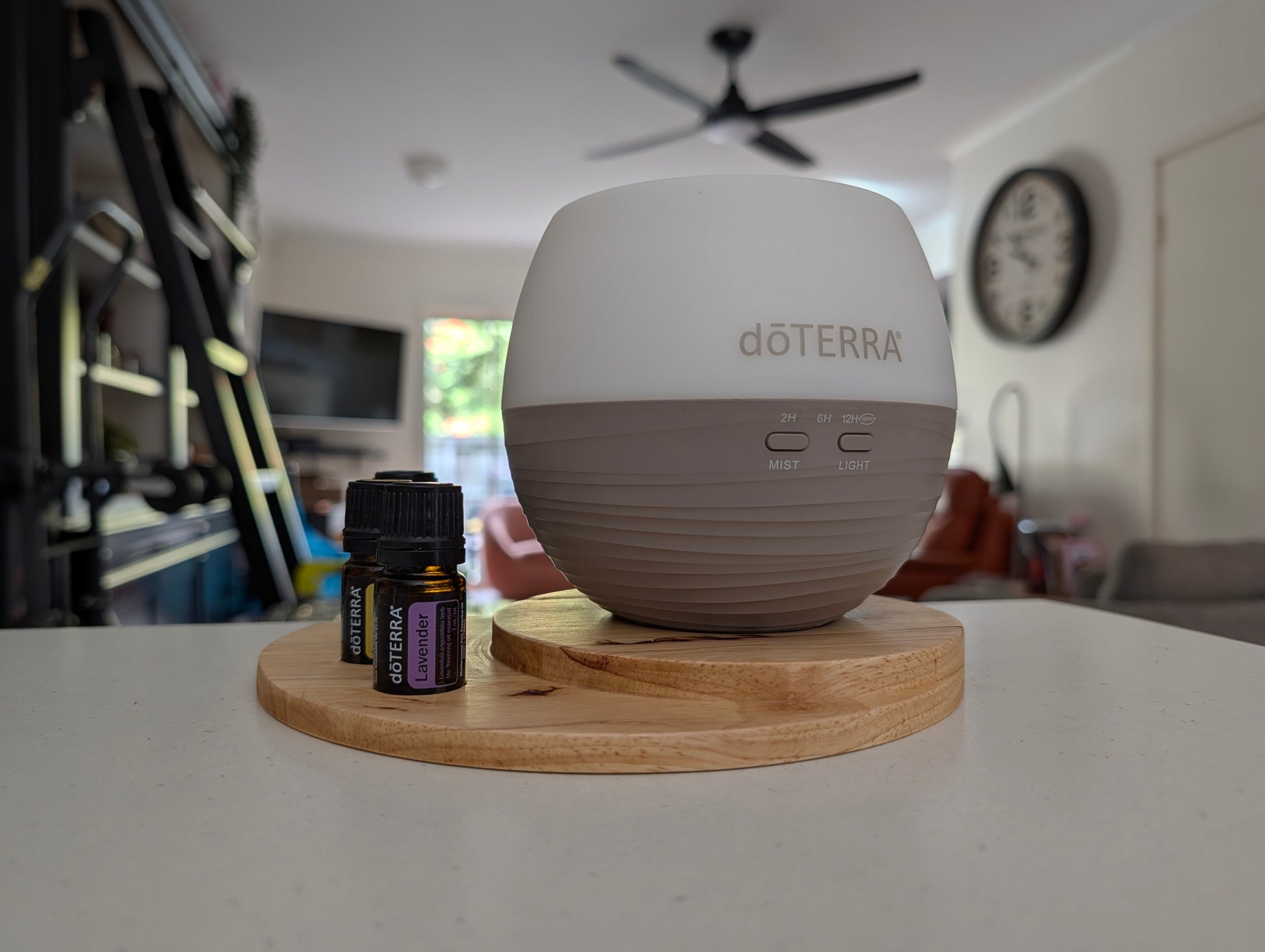 doTERRA essential oils and petal diffuser on a wooden stand with bottles in a home setting