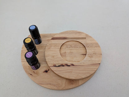 Wooden circular tray with essential oil bottles on a light gray background